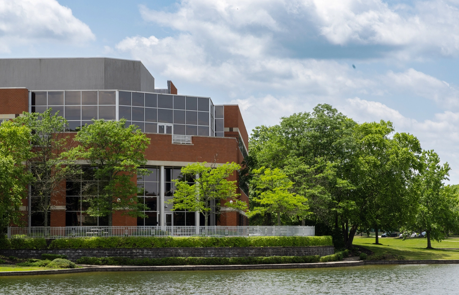 Corporate office complex overlooking landscaped pond with glass windows and manicured grounds