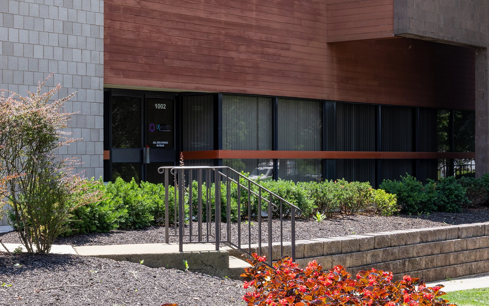 Office building exterior with landscaped shrubs accessible stairs and ground level windows on corporate campus