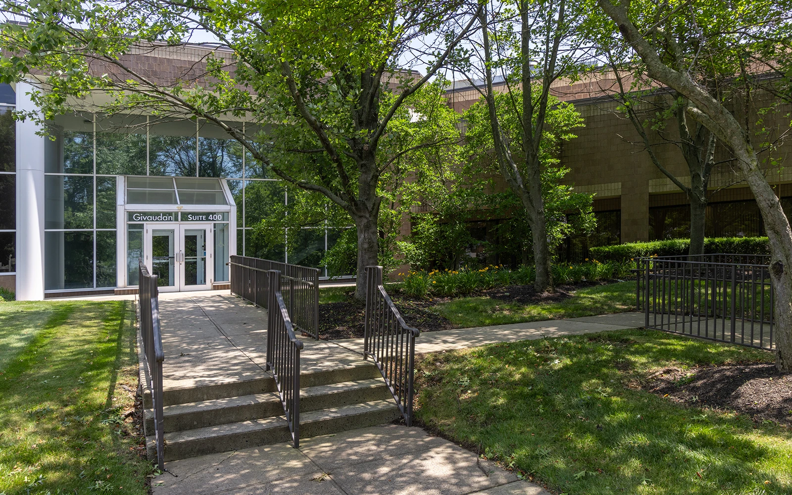 Corporate office exterior featuring accessible walkway glass lobby entrance and green landscaped grounds