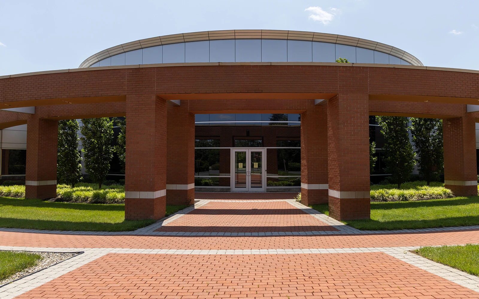 Symmetrical office building entrance featuring brick archway and landscaped walkway at Cedar Brook campus