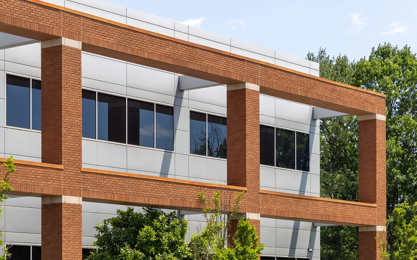 Sunlit office complex with curved architecture brick plaza and landscaped trees in Cranbury New Jersey
