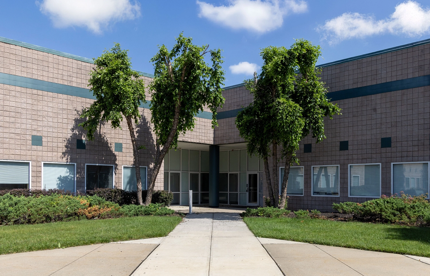 Corner entrance into a brick laboratory facility framed by two mature trees