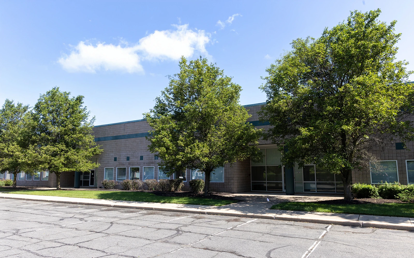 Single story office building with tree lined frontage and parking at Cedar Brook campus