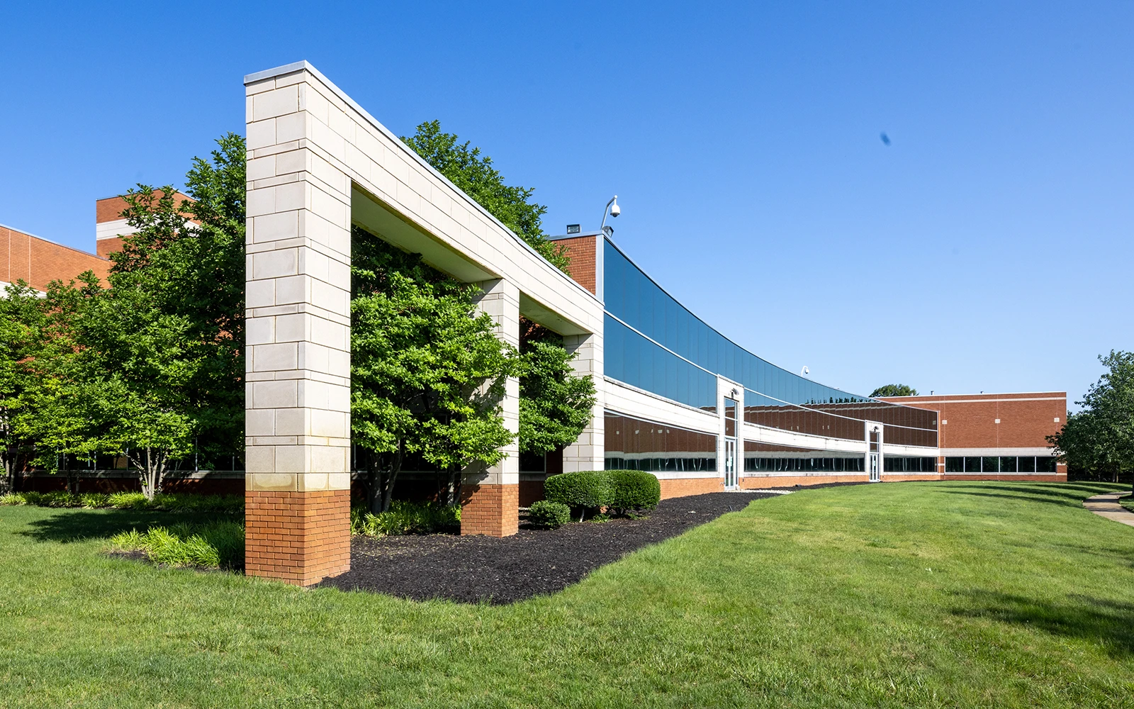 Curved glass office building exterior with landscaped lawn and modern architectural detailing