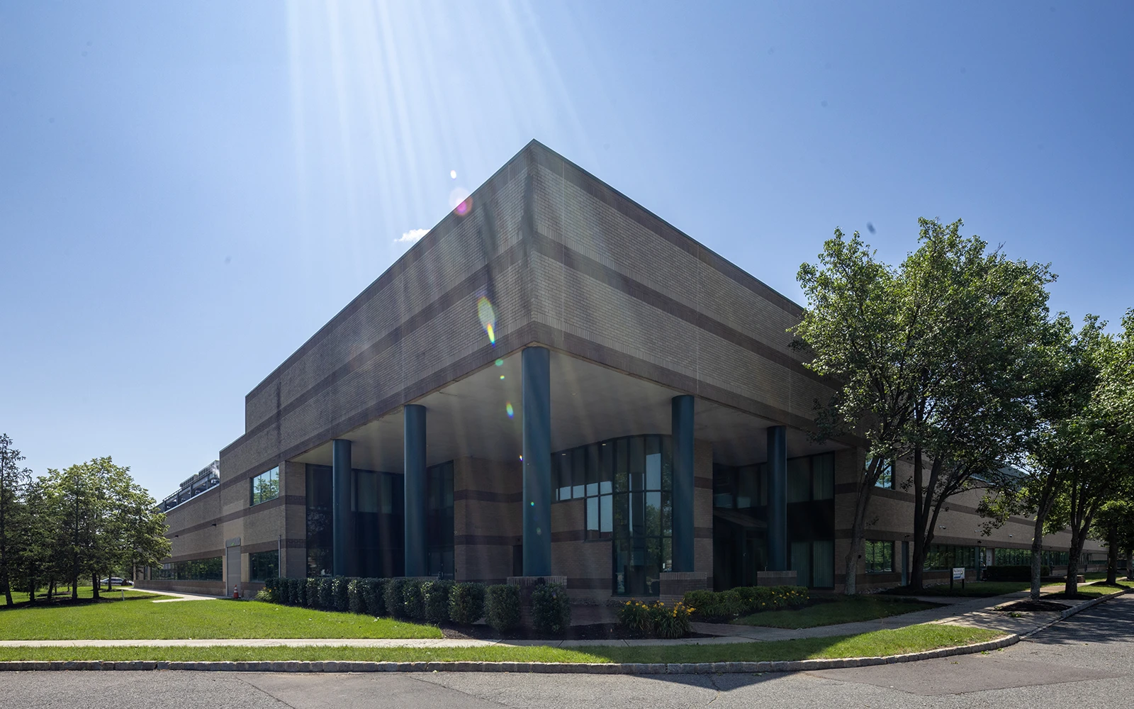 Professional office exterior with prominent columns angular architecture manicured landscaping and sunlight