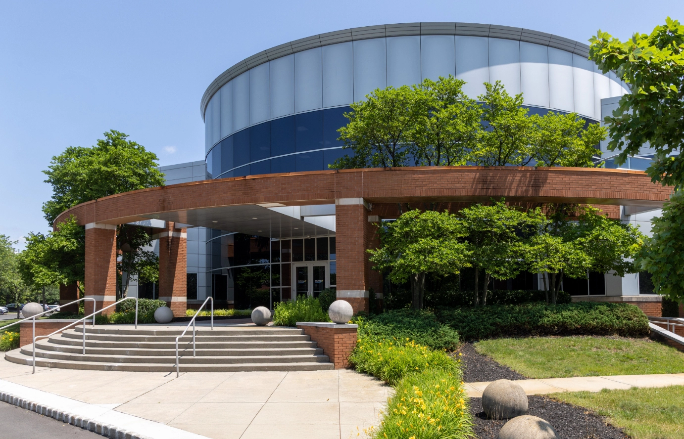 Main office building entrance with curved facade steps and mature trees at Cedar Brook campus