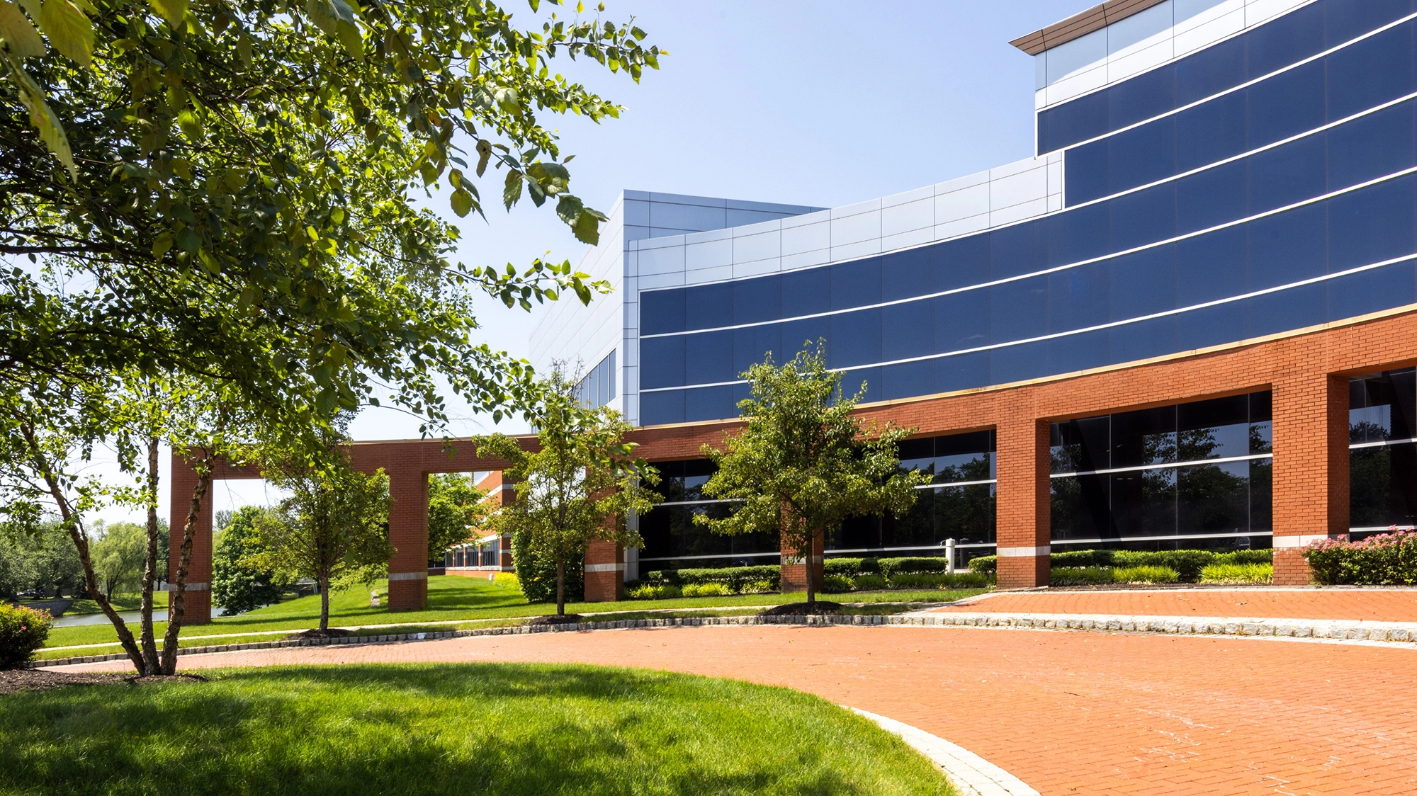 Glass office entrance with white column and landscaped greenery at Cedar Brook corporate center campus