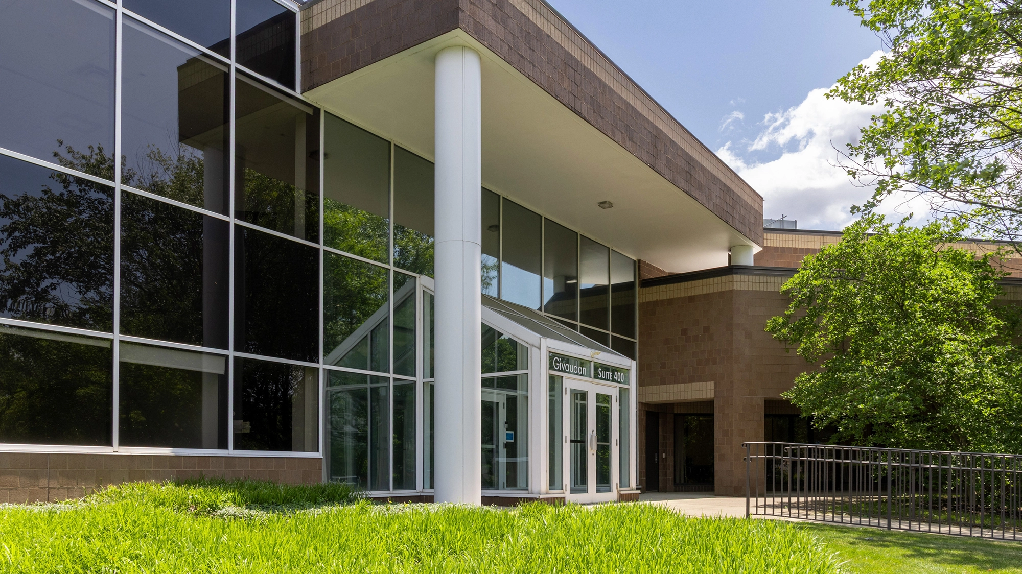 Office campus entrance with reflective windows brick exterior and accessible landscaped walkwa