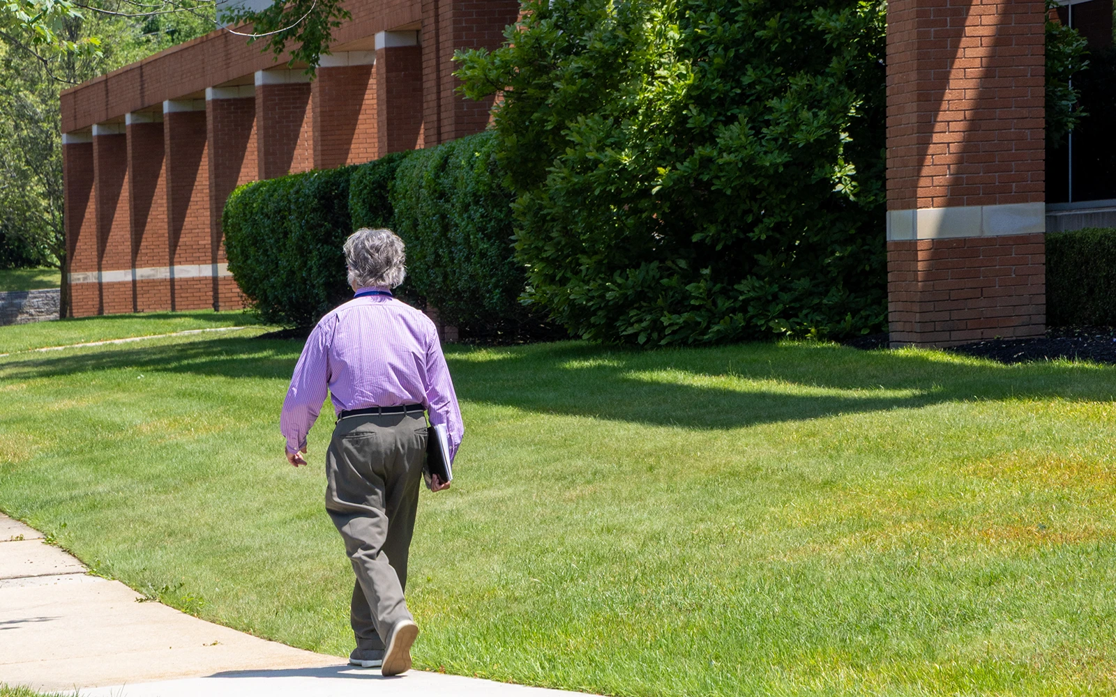 A man in a purple shirt strolling outside through a corporate science campus