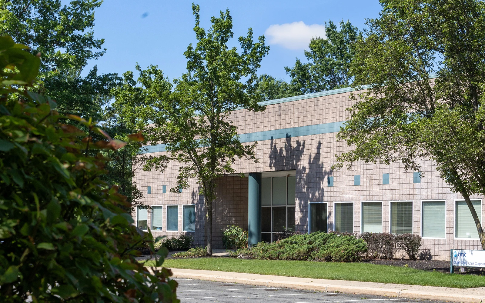 Modern corporate office exterior surrounded by mature trees and landscaped grounds in Cranbury