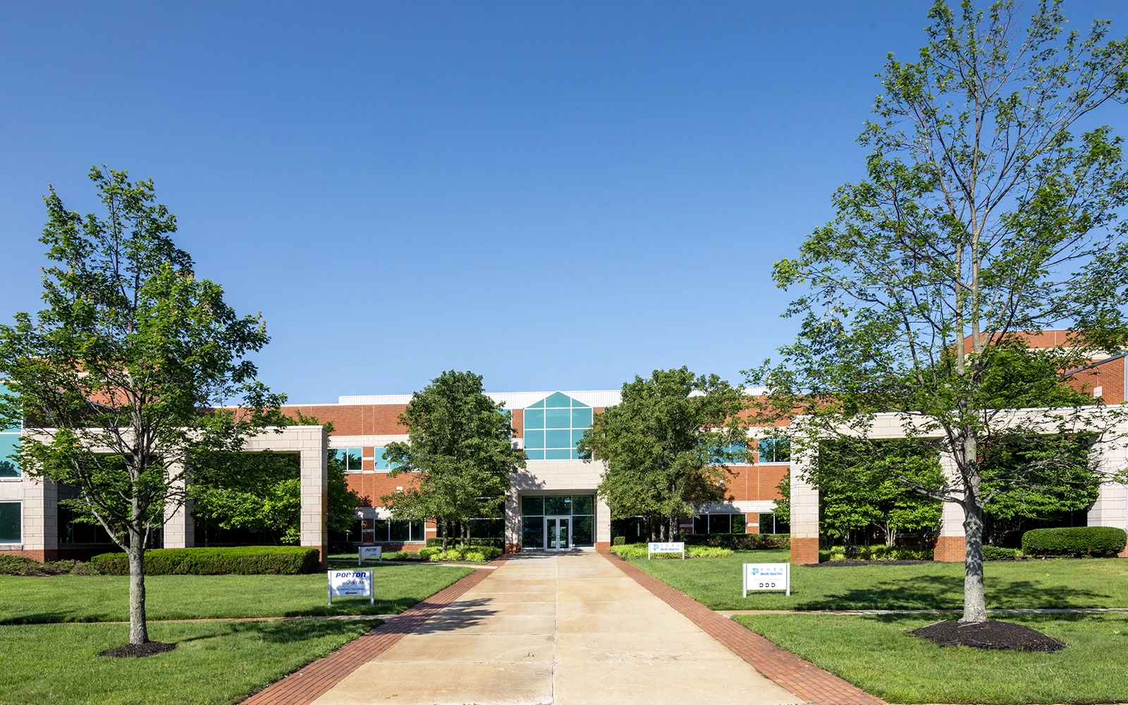 Professional business campus exterior featuring central entrance pathway green landscaping and modern facade
