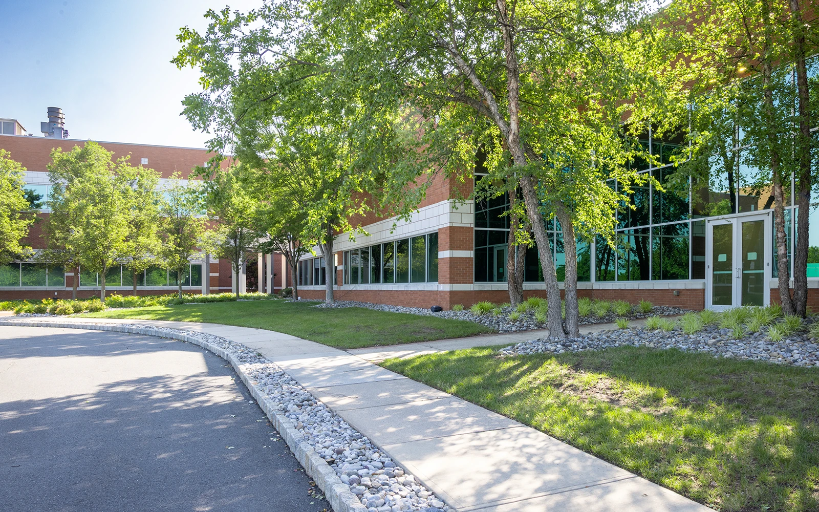 Professional business campus featuring brick office building greenery pathways and reflective glass facade