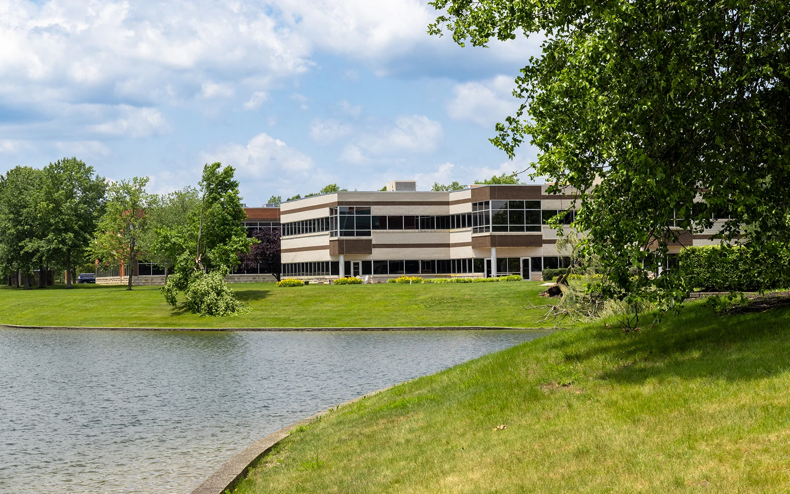 Corporate office building overlooking landscaped pond and green lawn at Cedar Brook campus Cranbury