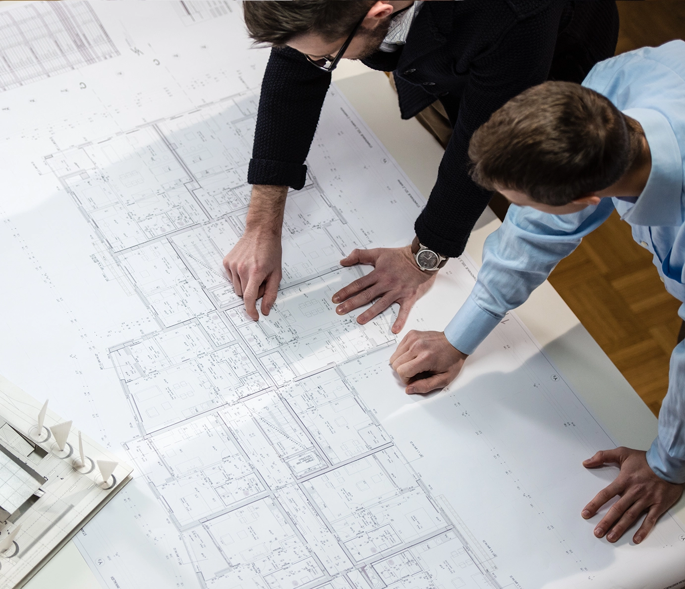 Architects reviewing detailed construction blueprints together on desk during collaborative building planning session
